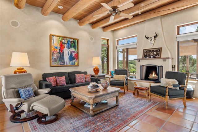 tiled living room featuring ceiling fan, wood ceiling, a wealth of natural light, and a large fireplace