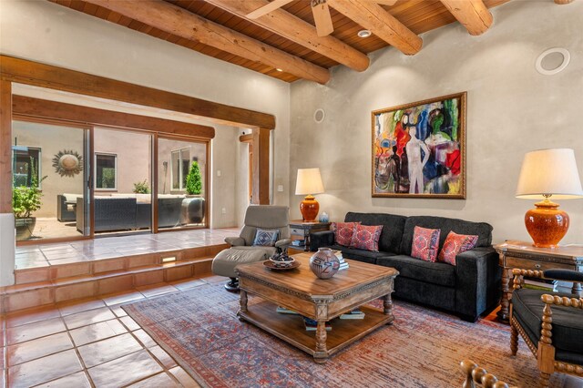 tiled living room with ceiling fan, beamed ceiling, and wooden ceiling