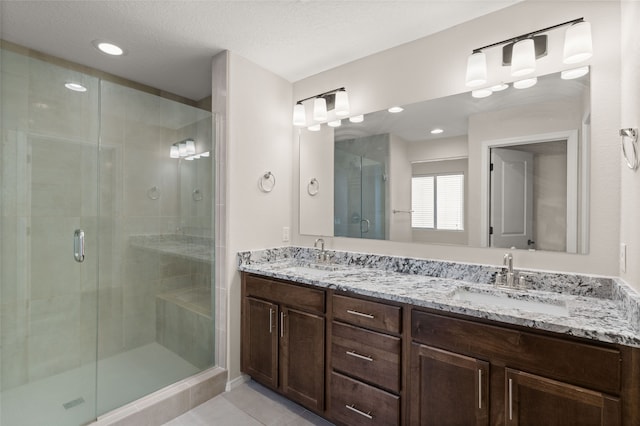 bathroom featuring tile patterned floors, vanity, an enclosed shower, and a textured ceiling