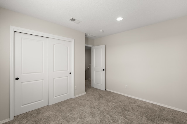 unfurnished bedroom with a closet, carpet, and a textured ceiling