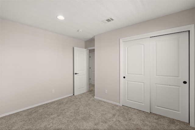 unfurnished bedroom featuring light carpet and a closet