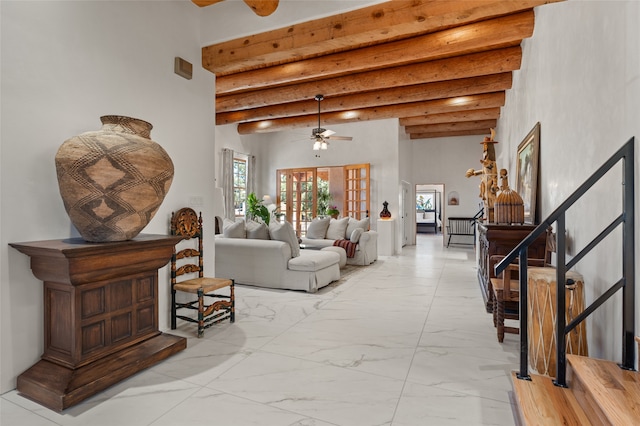 living room featuring ceiling fan, a high ceiling, and beamed ceiling