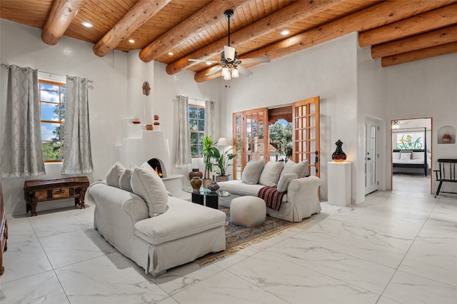 living room with ceiling fan, wood ceiling, a towering ceiling, and beamed ceiling