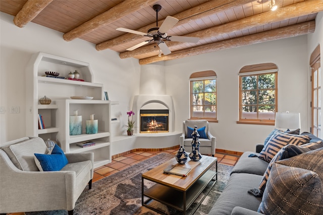 tiled living room featuring ceiling fan, beamed ceiling, wood ceiling, and a large fireplace