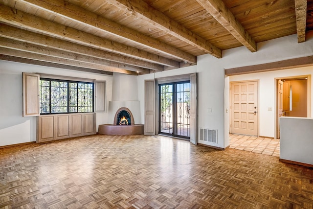 unfurnished living room with wooden ceiling, a lit fireplace, visible vents, and a wealth of natural light