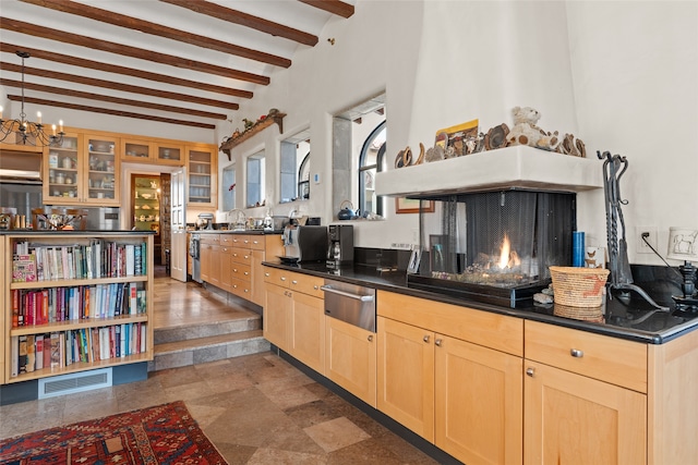 kitchen featuring beamed ceiling, light brown cabinets, and a multi sided fireplace