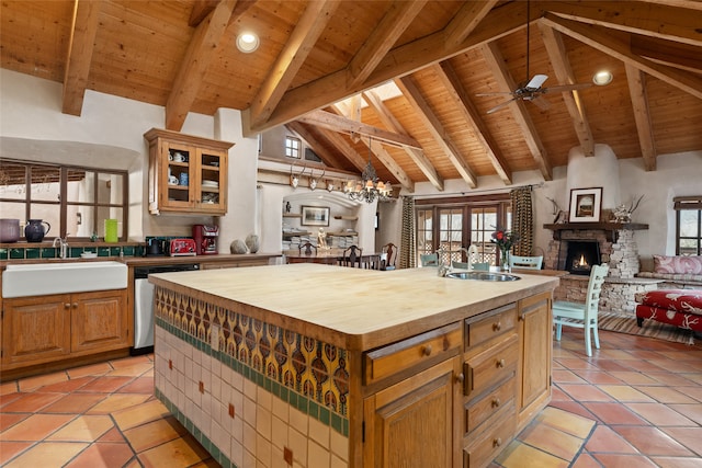 kitchen with wood ceiling, sink, dishwasher, a stone fireplace, and an island with sink