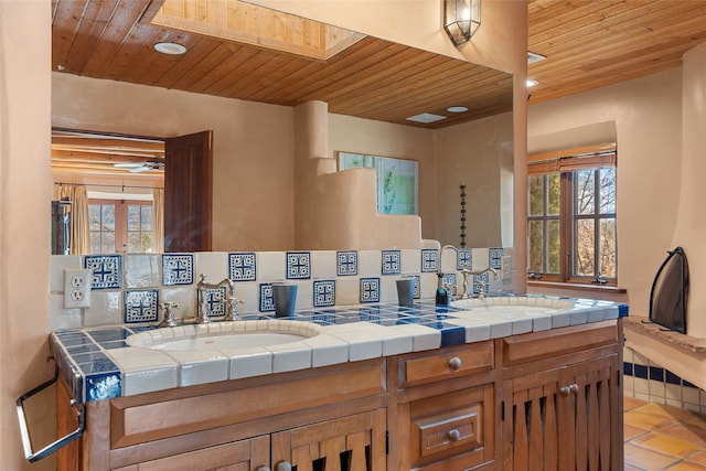 bathroom featuring tile patterned flooring, vanity, wooden ceiling, and a skylight