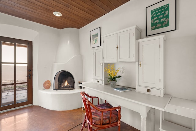 office space featuring a large fireplace, concrete floors, and wooden ceiling