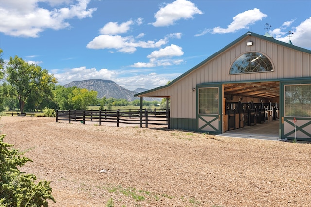 view of horse barn featuring a mountain view and a rural view