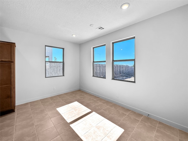 tiled spare room featuring a textured ceiling