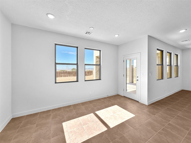 empty room with light tile patterned floors and a textured ceiling