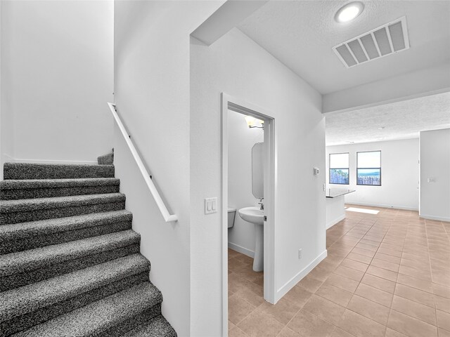 stairs featuring tile patterned floors and a textured ceiling