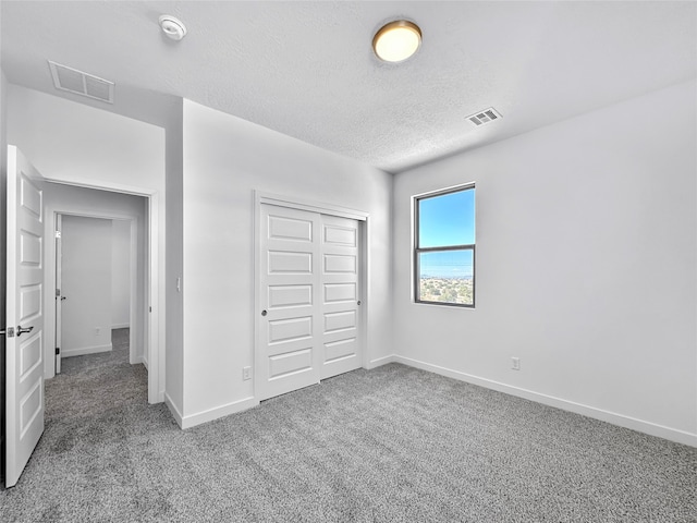 unfurnished bedroom featuring carpet flooring, a textured ceiling, and a closet