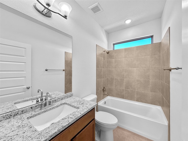 full bathroom with vanity, tile patterned floors, tiled shower / bath combo, toilet, and a textured ceiling