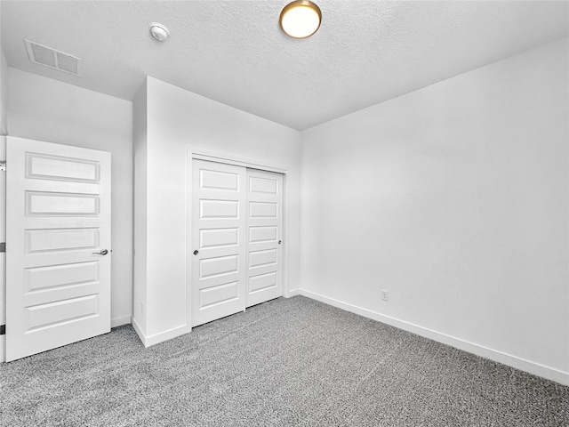 unfurnished bedroom featuring carpet flooring, a textured ceiling, and a closet