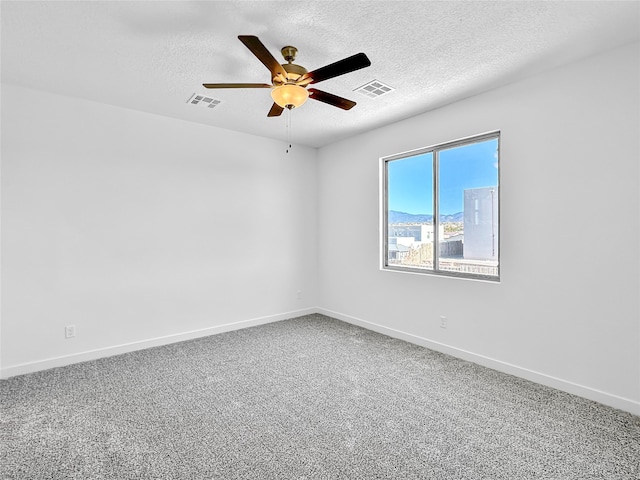 carpeted empty room with ceiling fan and a textured ceiling