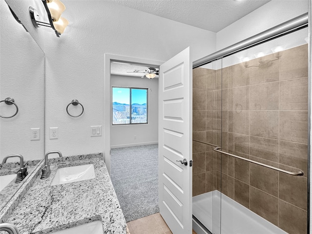 bathroom with ceiling fan, tile patterned flooring, a textured ceiling, vanity, and a shower with shower door