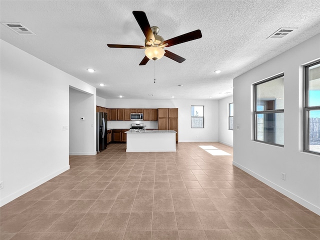 unfurnished living room with light tile patterned floors, a textured ceiling, and ceiling fan