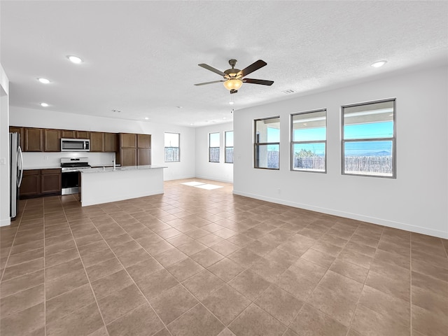 unfurnished living room with light tile patterned floors, a textured ceiling, ceiling fan, and sink