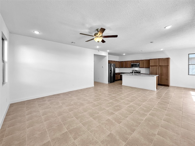 unfurnished living room featuring ceiling fan, light tile patterned floors, and a textured ceiling