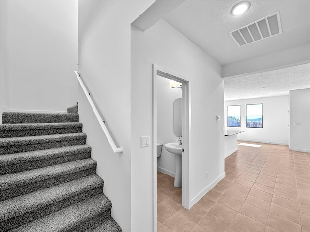 3497 Aster Ln, Santa Fe, NM 87507 - stairs featuring tile patterned floors, visible vents, baseboards, and a textured ceiling