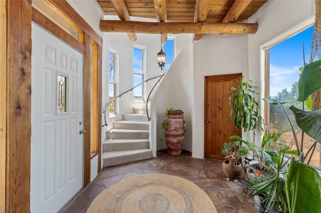 foyer entrance with stairway, beamed ceiling, and a wealth of natural light