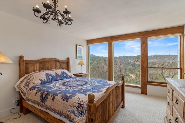 bedroom with light carpet, a wooded view, and a chandelier