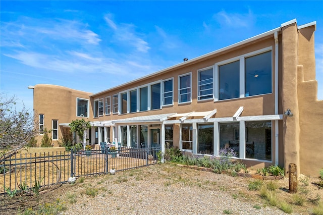 rear view of house with a patio, fence, and stucco siding