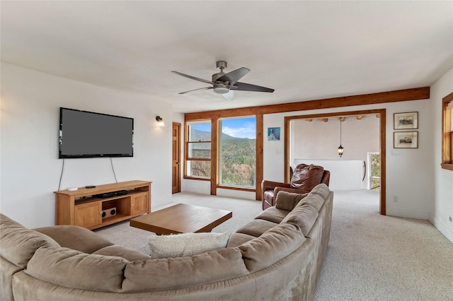 living area featuring light carpet, baseboards, and a ceiling fan