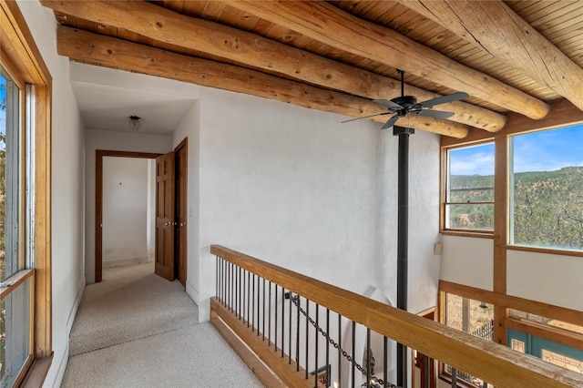 hallway featuring beam ceiling, carpet flooring, wooden ceiling, and baseboards