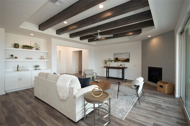 living room featuring dark wood-type flooring, a large fireplace, and beamed ceiling