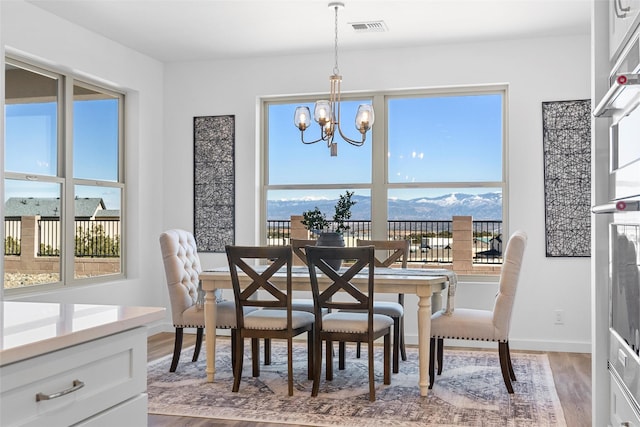 dining area featuring a mountain view, hardwood / wood-style flooring, and a chandelier