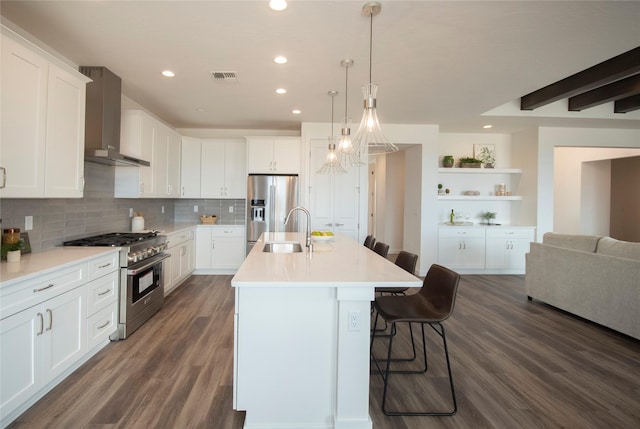 kitchen featuring white cabinetry, appliances with stainless steel finishes, a kitchen island with sink, and wall chimney exhaust hood