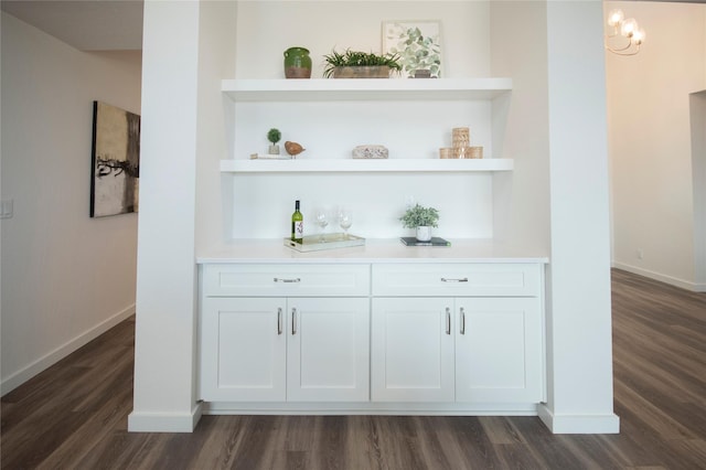 bar with white cabinetry, dark hardwood / wood-style floors, and built in shelves