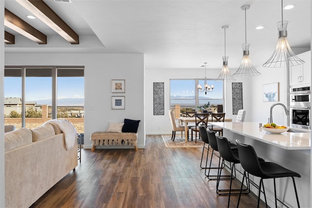 dining room with a healthy amount of sunlight, sink, a notable chandelier, and dark hardwood / wood-style flooring