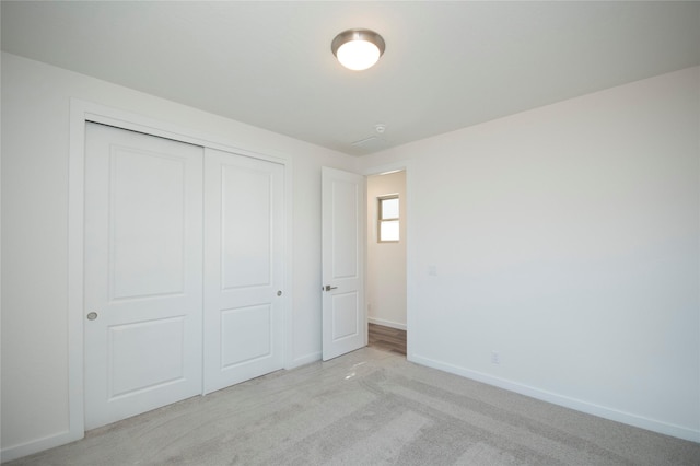 unfurnished bedroom featuring a closet and light carpet