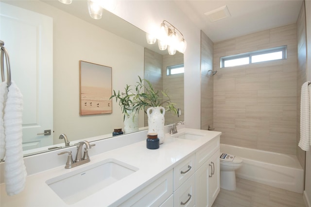 full bathroom with tiled shower / bath, vanity, and toilet