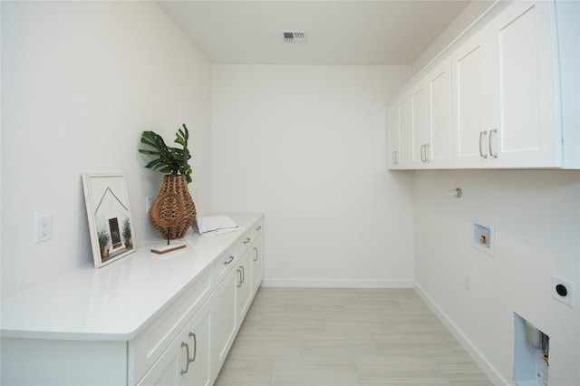 laundry area with electric dryer hookup, hookup for a washing machine, and cabinets