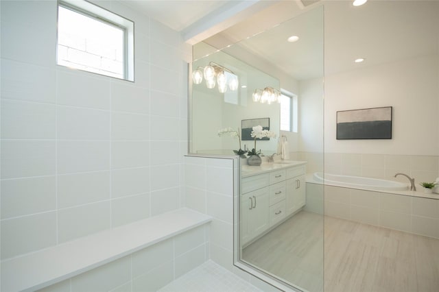 bathroom with vanity and tiled bath