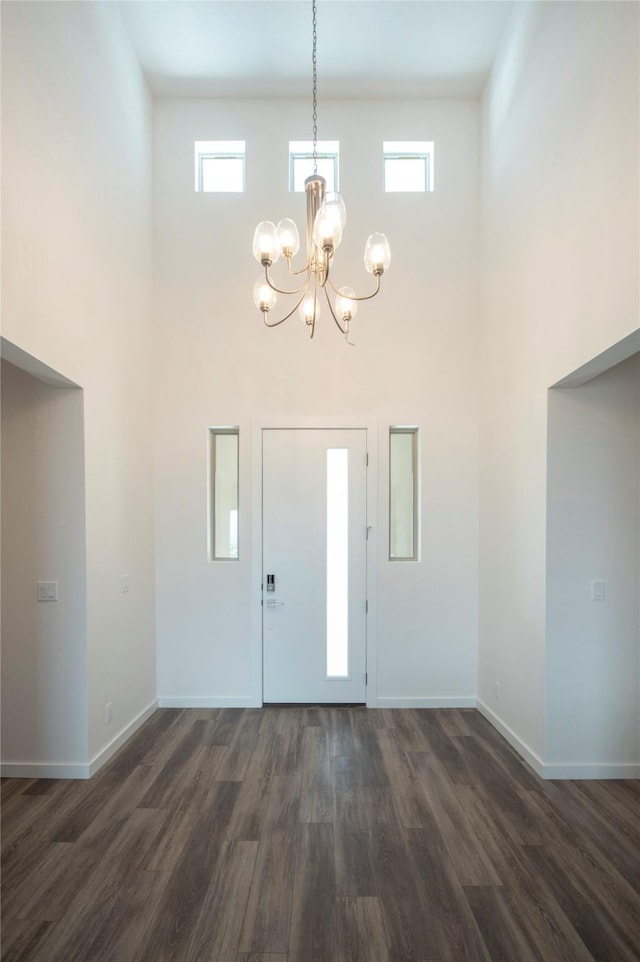 foyer with a high ceiling, a wealth of natural light, a notable chandelier, and dark hardwood / wood-style flooring