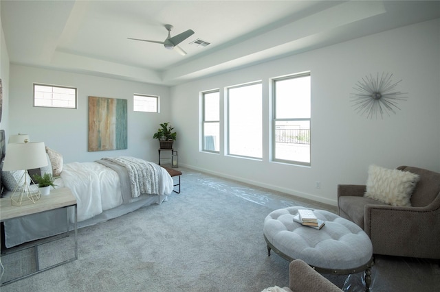 bedroom featuring ceiling fan, a raised ceiling, and light carpet