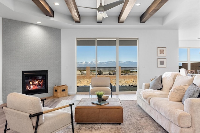 living room featuring beamed ceiling, ceiling fan, a mountain view, and light hardwood / wood-style floors