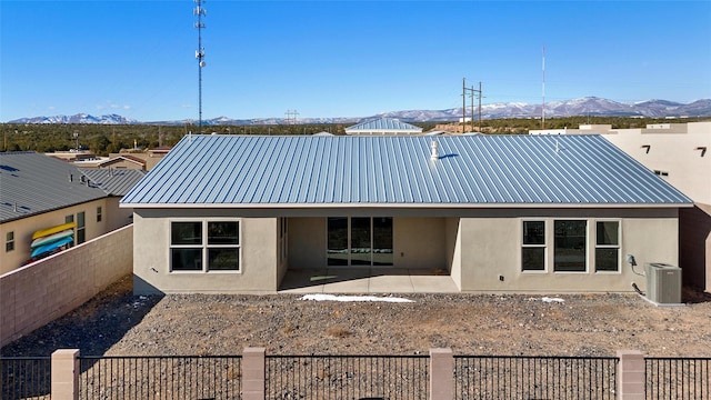 rear view of property with central AC unit, a mountain view, and a patio area