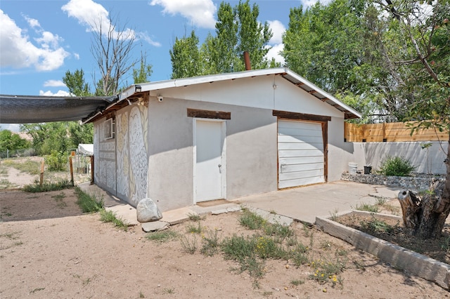 garage featuring fence and concrete driveway