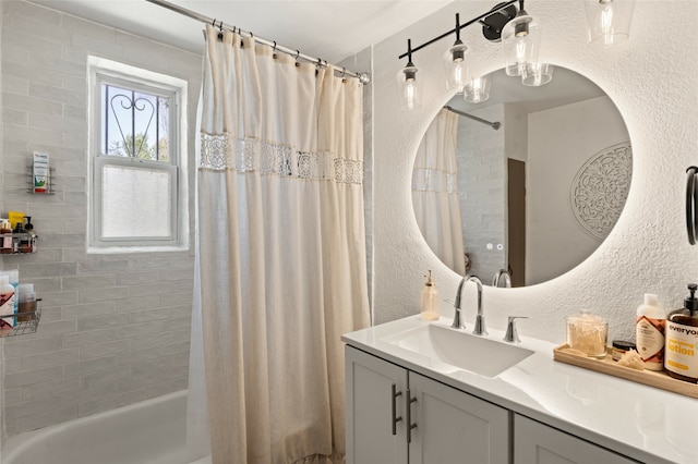 bathroom featuring shower / tub combo with curtain, a textured wall, and vanity