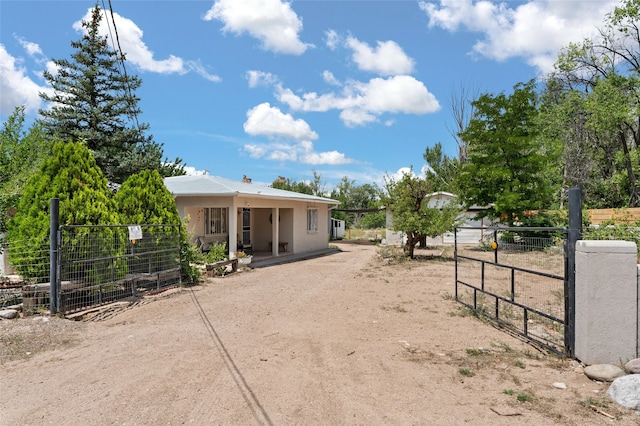 view of front of property with a gate, dirt driveway, fence, and stucco siding