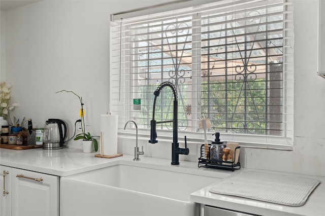 kitchen with white cabinetry, light countertops, and a sink