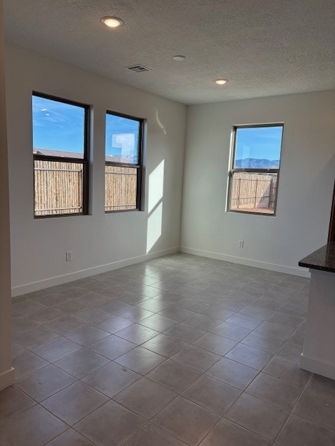 tiled empty room featuring a textured ceiling