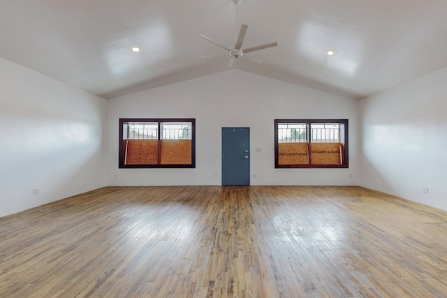 empty room featuring hardwood / wood-style flooring, ceiling fan, vaulted ceiling, and a wealth of natural light